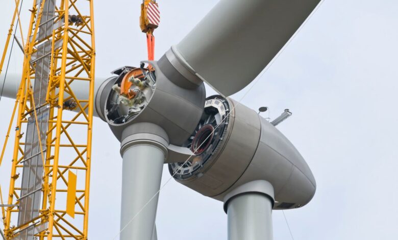 A crane positions the rotor of a wind turbine during construction.